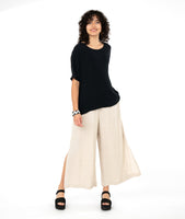 model in a black tee with a wide leg oatmeal color pant with a split at either side seam