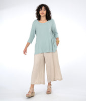 model in a long blue top with a wide leg oatmeal color pant, with a split on either side