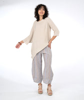 model in an asymmetrical top with a wide leg striped pant, tapering at the ankle