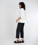 model in a slim black pant with a split at the ankle, with a boxy white button down