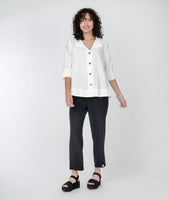 model in a slim black pant with a split at the ankle, with a boxy white button down