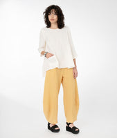model in a yellow top with a hankerchief hem and a wide leg yellow pant 
