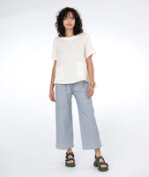 model in a boxy white top with a blue and white pinstripe pant with asymmetrical pockets