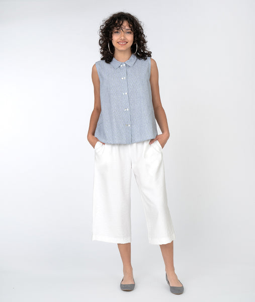 model in a sleeveless pinstriped button down top with a white wide leg cropped pant