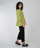 model in a slim black pant with a long button down blouse in  lime