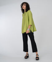 model in a slim black pant with a long button down blouse in lime