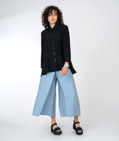 model in a wide leg blue pant with a long, flowy black button down blouse