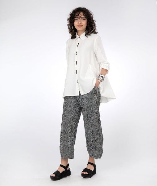 model in a black and white striped pant with a long, flowy white button down blouse