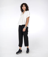 model in a slim black pant with a white short sleeve button down vneck top