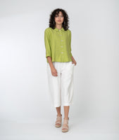 model in a white cropped pant with a lime green button up blouse