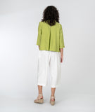 model in a white cropped pant with a lime green button up blouse
