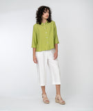 model in a white cropped pant with a lime green button up blouse