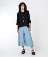 model in a black button down top with a wide leg blue pant